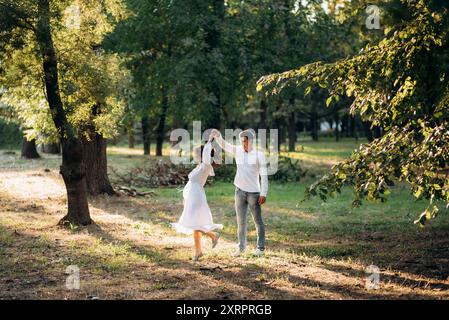 guy et une fille marchent le long des chemins d'un parc forestier entre de grands arbres Banque D'Images