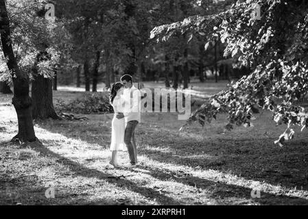 guy et une fille marchent le long des chemins d'un parc forestier entre de grands arbres Banque D'Images