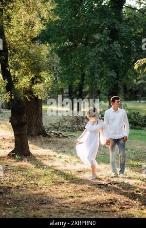 guy et une fille marchent le long des chemins d'un parc forestier entre de grands arbres Banque D'Images