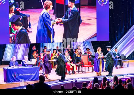 Cérémonie de remise des diplômes au Butterworth Hall, Université de Warwick. Étudiant sur scène pour recueillir son diplôme et se serrer la main avec le président. Banque D'Images