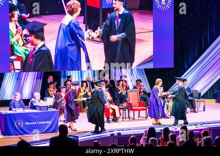 Cérémonie de remise des diplômes au Butterworth Hall, Université de Warwick. Étudiant sur scène pour recueillir son diplôme et se serrer la main avec le président. Banque D'Images