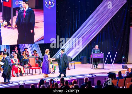 Cérémonie de remise des diplômes au Butterworth Hall, Université de Warwick. Étudiant sur scène pour recueillir son diplôme et se serrer la main avec le président. Banque D'Images