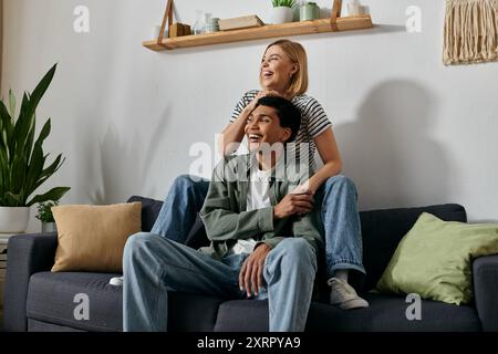 Un jeune couple interracial se détend et profite de la compagnie de l'autre dans leur appartement moderne. Banque D'Images