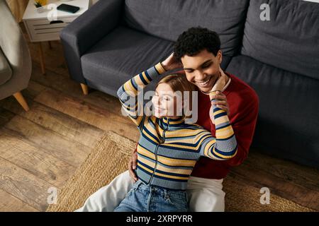 Un couple multiculturel heureux se détend à l'étage de leur appartement, profitant de moments de qualité ensemble. Banque D'Images