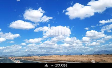 Ciel bleu lumineux avec nuages fluvieux et construction de routes dans le désert Banque D'Images