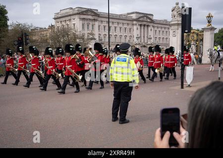 Surveillé par des foules de touristes, un officier de police du met Community support assure la sécurité des gardes qui retournent dans leur caserne après la cérémonie quotidienne de relève de la garde au Palais de Buckingham, le 5 août 2024, à Londres, en Angleterre. Banque D'Images