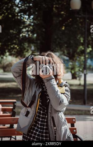 Photographe fille aux cheveux bouclés bruns prend une photo de vous Banque D'Images