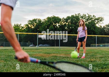 Une fille jouant au tennis avec son père sur le terrain Banque D'Images