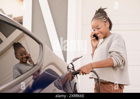 Jeune dame au téléphone branchant dans le chargeur de voiture Banque D'Images