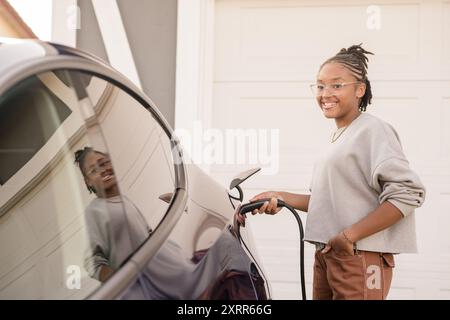 Jeune femme branchant un chargeur à la maison Banque D'Images