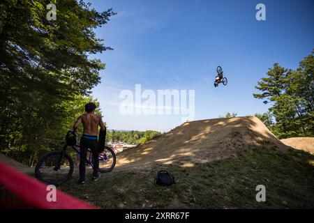 Coureur de slopestyle effectuant un retournement dans un parc de VTT Banque D'Images