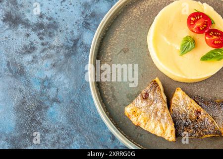 Filet de poisson de mer frit et un plat d'accompagnement de purée de pommes de terre en gros plan dans une assiette sur la table. Service de restaurant. Vue de dessus. Placer pour le texte. Enfant Banque D'Images