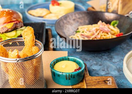 Lanières de poulet avec sauce sur le fond d'un hamburger, spaghetti et purée de pommes de terre. Ensemble de nourriture du menu enfant. Dîner. Service de restaurant Banque D'Images