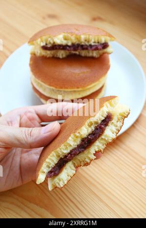 Main tenant l'appétissant Split Dorayaki, un crêpe japonais avec garniture Azuki Red Bean Paste Banque D'Images