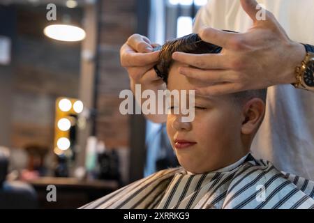 Un jeune garçon se fait couper les cheveux dans un salon de coiffure Banque D'Images