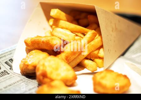 Sur la table, il y a une boîte de nuggets de poulet et de frites. Le repas comprend de la restauration rapide et de la nourriture frite, qui sont des plats de base populaires dans beaucoup Banque D'Images