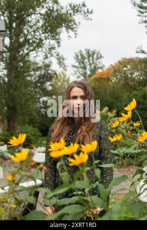 Belle femme debout dans des fleurs jaunes d'automne dans le parc en plein air Banque D'Images