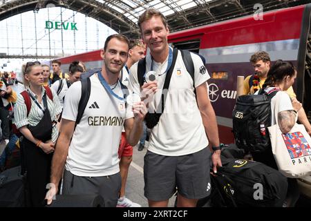 Cologne, Allemagne. 12 août 2024. Le duo allemand de Beach volley Nils Ehlers (R) et Clemens Wickler présentent leur médaille d’argent à leur arrivée à la gare centrale de Cologne le jour de leur départ après la clôture des Jeux Olympiques. Crédit : Sebastian Kahnert/dpa/Alamy Live News Banque D'Images