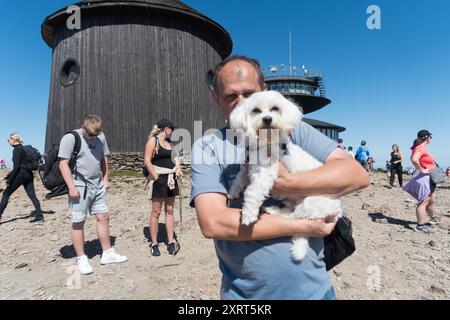 Un homme avec un chien dans les bras au sommet de Sněžka République tchèque Banque D'Images