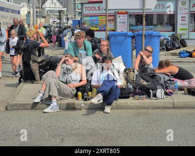 Newquay, Cornouailles, Royaume-Uni. 12 août 2024. Exodus au festival Boardmasters surf and Music. L'immense ville de tente est abandonnée à Watergate Bay. De nombreux campeurs quittent leurs tentes et leur équipement plutôt que de les démonter et de les ramener chez eux. Les travailleurs bénévoles passent au crible les séquelles pour réutiliser ou acheminer de l'équipement récupérable à des organismes de bienfaisance sans abri. Les fans fatigués attendent à Newquay les trains et les entraîneurs pour les emmener à la maison et les douches chaudes. Crédit : Robert Taylor/Alamy Live News Banque D'Images