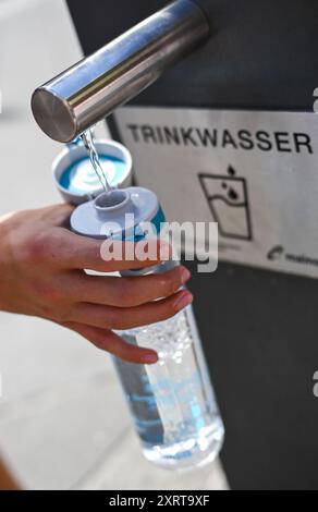 12 août 2024, Hesse, Francfort-sur-le-main : par temps chaud en été, un jeune homme remplit sa bouteille d'eau à la fontaine de la Paulsplatz. Photo : Arne Dedert/dpa Banque D'Images