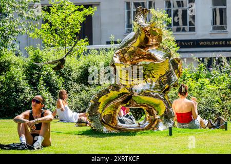 Londres, Royaume-Uni. 12 août 2024. Les travailleurs et les visiteurs profitent d'une pause à Hanover Square, certains à l'ombre et d'autres au soleil, autour d'une sculpture temporaire Power Tower, par Lynda Benglis, fournie par Pace Gallery - une autre mini vague de chaleur de fin d'été automne, conduit au temps ensoleillé et amène les gens dehors à l'heure du déjeuner à Londres. Crédit : Guy Bell/Alamy Live News Banque D'Images