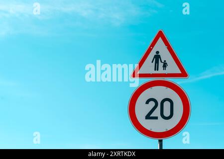 UK Road Signs Children Crossing et Road 20 mile par heure limite de vitesse sur fond de ciel bleu avec espace de copie. Soyez prévenant envers les autres Banque D'Images