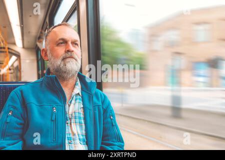 homme barbu heureux en veste chaude bleue dans un bus ou un tram. Concept de style de vie Banque D'Images