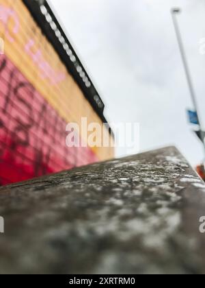 Un bâtiment couvert de graffiti avec un panneau sur le côté qui dit "No parking". Le bâtiment est entouré d'un mur de béton et d'une balustrade métallique. Le ciel Banque D'Images