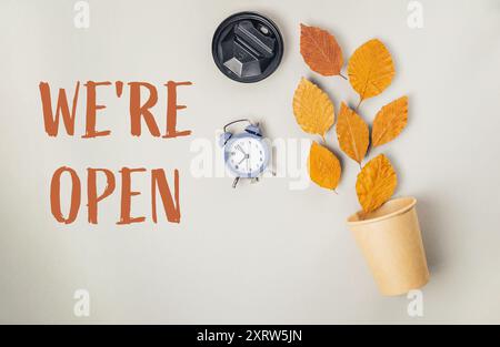 Une horloge et une tasse de café sont sur une table avec les mots nous sommes ouverts écrits en dessous d'eux Banque D'Images