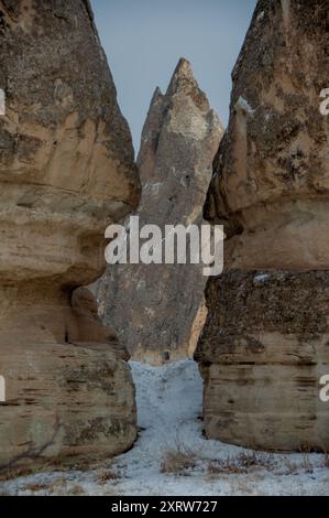 Cheminées de fées enneigées en Cappadoce, Turquie, avec d'anciennes habitations de grottes sculptées dans les formations rocheuses uniques Banque D'Images
