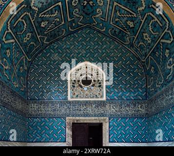 Intérieur de mosquée carrelé avec motifs géométriques et calligraphie arabe avec une fenêtre décorative voûtée Banque D'Images