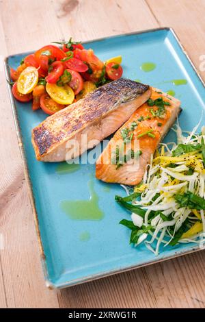 Une assiette de filets de saumon frais saisis avec salade de tomates maison et légumes verts. Banque D'Images