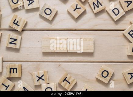 Une planche de bois avec un puzzle de mots croisés dessus. Le puzzle est composé de blocs de bois et de lettres Banque D'Images