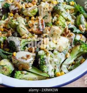 Un plat de légumes frais carbonisés avec choux de bruxelles, fromage grillé, tiges de brocoli, maïs doux, noix écrasées etvinaigrette. Banque D'Images