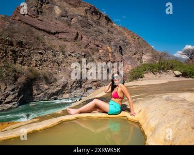 Jeune femme péruvienne portant un bikini et un short pose dans les sources thermales de Santo Tomas près de la rivière à Abancay, au Pérou Banque D'Images