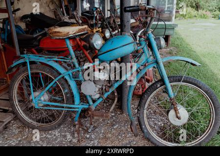 Un vélo motorisé vintage est garé dans un hangar rustique. Banque D'Images