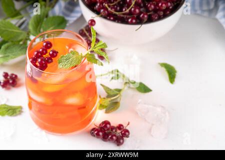 Red Currant Caipirinha, limonade ou boisson de sangria avec des glaçons et du jus de citron vert, sur un espace de copie de fond de table de cuisine blanc Banque D'Images