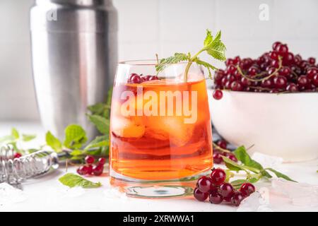 Red Currant Caipirinha, limonade ou boisson de sangria avec des glaçons et du jus de citron vert, sur un espace de copie de fond de table de cuisine blanc Banque D'Images