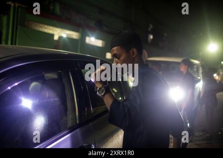 Dhaka, Bangladesh. 12 août 2024. Un étudiant vérifie une voiture la nuit lors d'une patrouille communautaire dans son quartier en l'absence de forces de l'ordre. Des volontaires patrouillent dans les quartiers en l'absence de forces de police bangladaises, pendant la nuit à Dhaka. Le lauréat du prix Nobel Muhammad Yunus et son gouvernement intérimaire nouvellement nommé se sont mis en route le 9 août pour rétablir « la loi et l'ordre » après un soulèvement mené par des étudiants et des manifestations de masse meurtrières qui ont forcé son prédécesseur Hasina à l'exil. Crédit : SOPA images Limited/Alamy Live News Banque D'Images