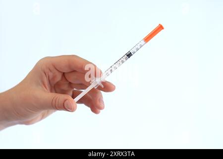 Seringue à insuline. La main d'une femme tient une seringue sur un fond blanc, gros plan. Seringue à insuline pour diabète. Traitement du diabète. Médecine et santé Banque D'Images