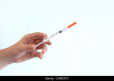 Seringue à insuline. La main d'une femme tient une seringue sur un fond blanc, gros plan. Seringue à insuline pour diabète. Traitement du diabète. Médecine et santé Banque D'Images