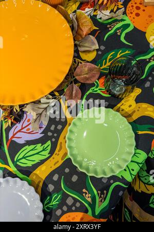 assiettes vertes et oranges et blanches sur nappe colorée et verre vert. Photo de haute qualité Banque D'Images