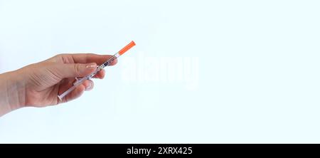 Seringue à insuline. La main d'une femme tient une seringue sur un fond blanc, gros plan. Seringue à insuline pour diabète. Traitement du diabète. Médecine et santé Banque D'Images