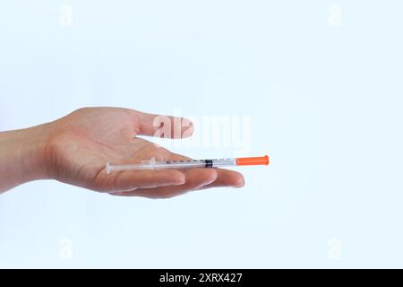 Seringue à insuline. La main d'une femme tient une seringue sur un fond blanc, gros plan. Seringue à insuline pour diabète. Traitement du diabète. Médecine et santé Banque D'Images