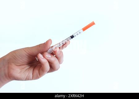 Seringue à insuline. La main d'une femme tient une seringue sur un fond blanc, gros plan. Seringue à insuline pour diabète. Traitement du diabète. Médecine et santé Banque D'Images