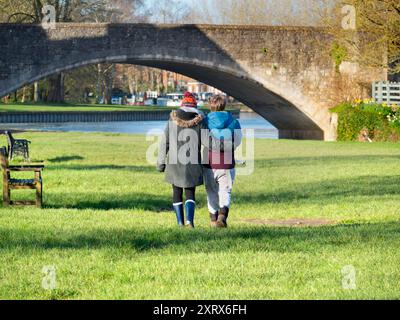 Abingdon prétend être la plus ancienne ville d'Angleterre. C'est son célèbre pont de pierre médiéval, vu par un beau matin d'été. Le pont a été commencé en 1416 et achevé en 1422, en utilisant du calcaire local. Ici, nous voyons un couple câlin marchant sur les rives de la Tamise vers le pont au lever du soleil. Banque D'Images