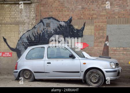 Londres, Royaume-Uni. 12 août 2024. Une nouvelle œuvre d'art de Banksy apparaît sur un mur à Charlton, représentant un rhinocéros qui devient intime avec une voiture avec un cône de circulation sur son capot. Il s'agit de la 8ème nouvelle œuvre d'art sur le thème des animaux en huit jours dans la capitale par l'insaisissable artiste de rue. (Photo de Vuk Valcic/SOPA images/SIPA USA) crédit : SIPA USA/Alamy Live News Banque D'Images