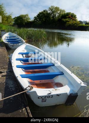 Fondé en 1921 et situé sur une belle partie de la Tamise dans l'Oxfordshire, Radley Boathouse sert Radley College et les amateurs d'aviron locaux depuis plus d'un siècle. Ici, nous voyons deux bateaux à rames amarrés par sa jetée, tôt par un beau matin d'été. Banque D'Images