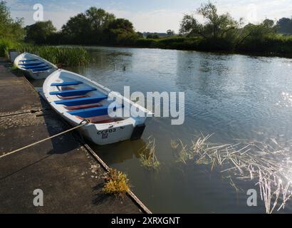 Fondé en 1921 et situé sur une belle partie de la Tamise dans l'Oxfordshire, Radley Boathouse sert Radley College et les amateurs d'aviron locaux depuis plus d'un siècle. Ici, nous voyons deux bateaux à rames amarrés par sa jetée, tôt par un beau matin d'été. Banque D'Images